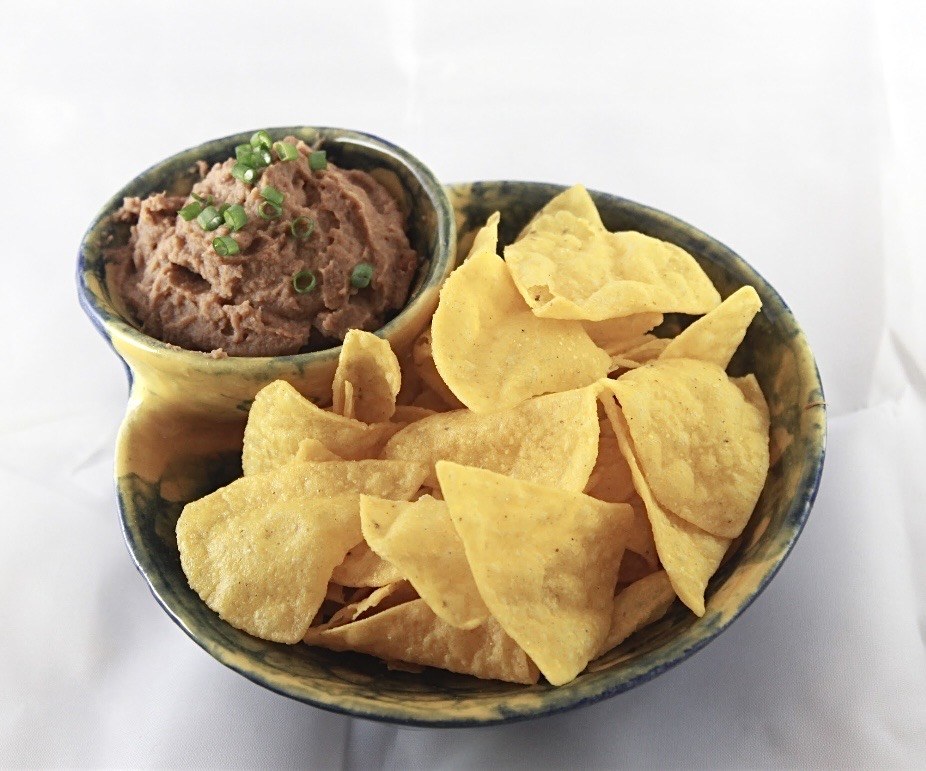 Blue and yellow ceramic chip-and-dip bowl served with tortilla chips and dip