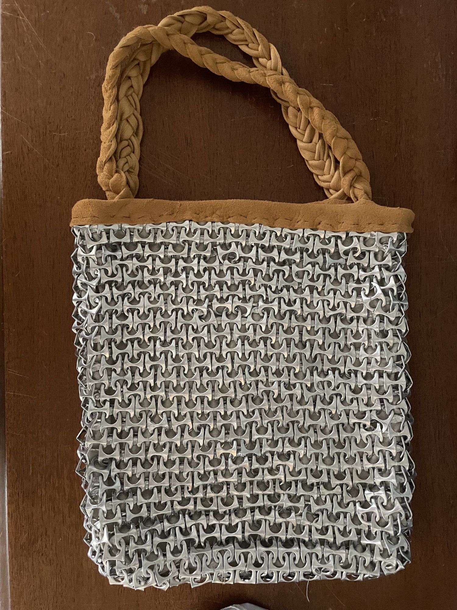 Tote bag made from hundreds of interlinked aluminium can pull-tabs with a braided fabric handle