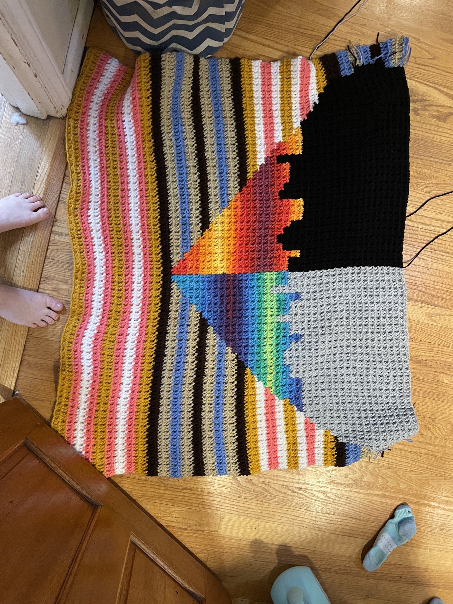 Large crocheted blanket in stripes with a geometric rainbow and black panel