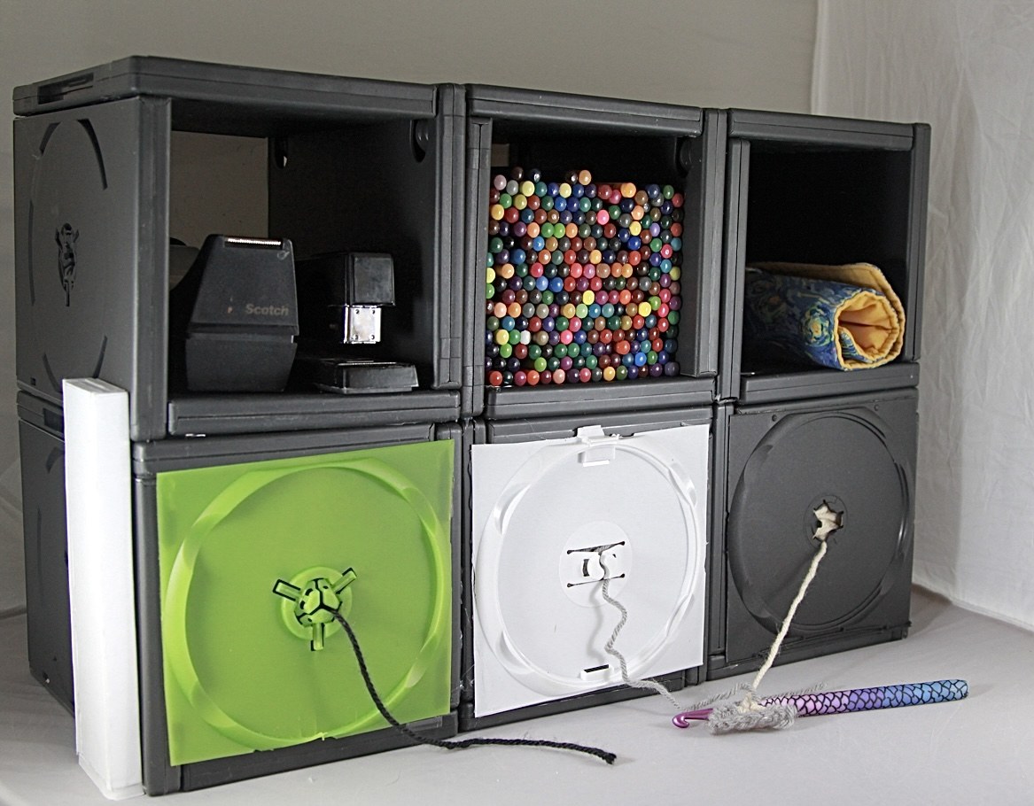 Modular black desk organizer holding craft tools, beads, yarn and fabric