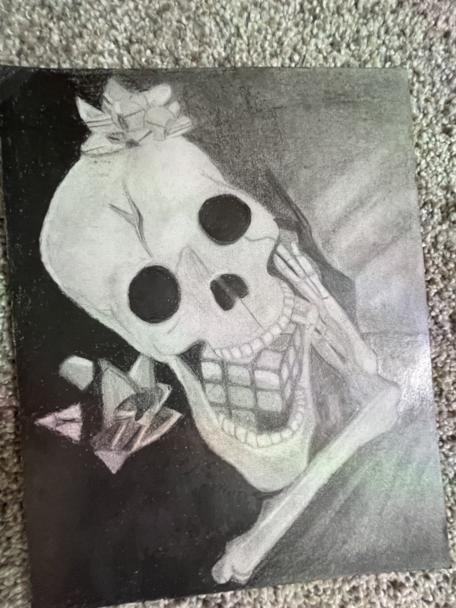Charcoal drawing of a human skull at an angle with dramatic light and shadow