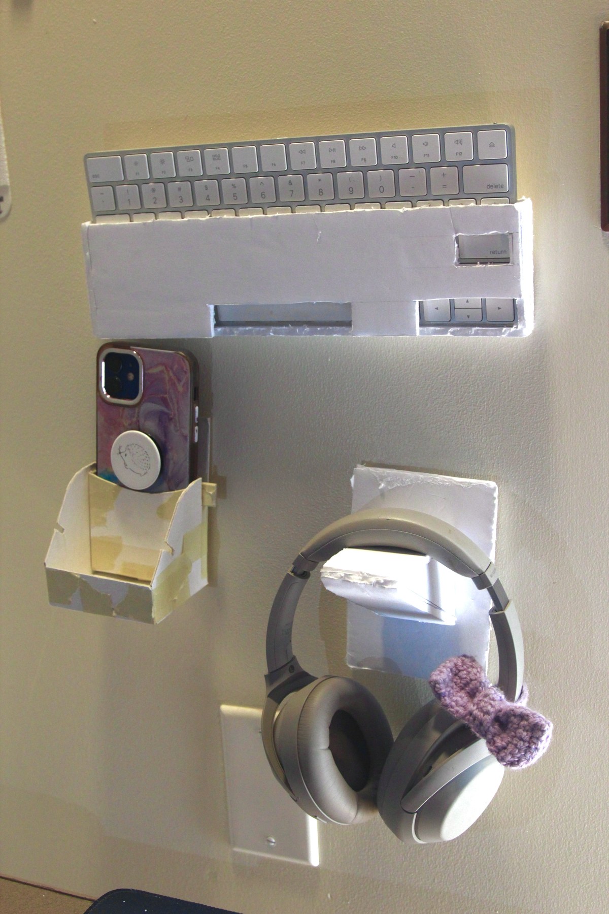 Wall-mounted foam-core organizer holding a keyboard, phone and headphones